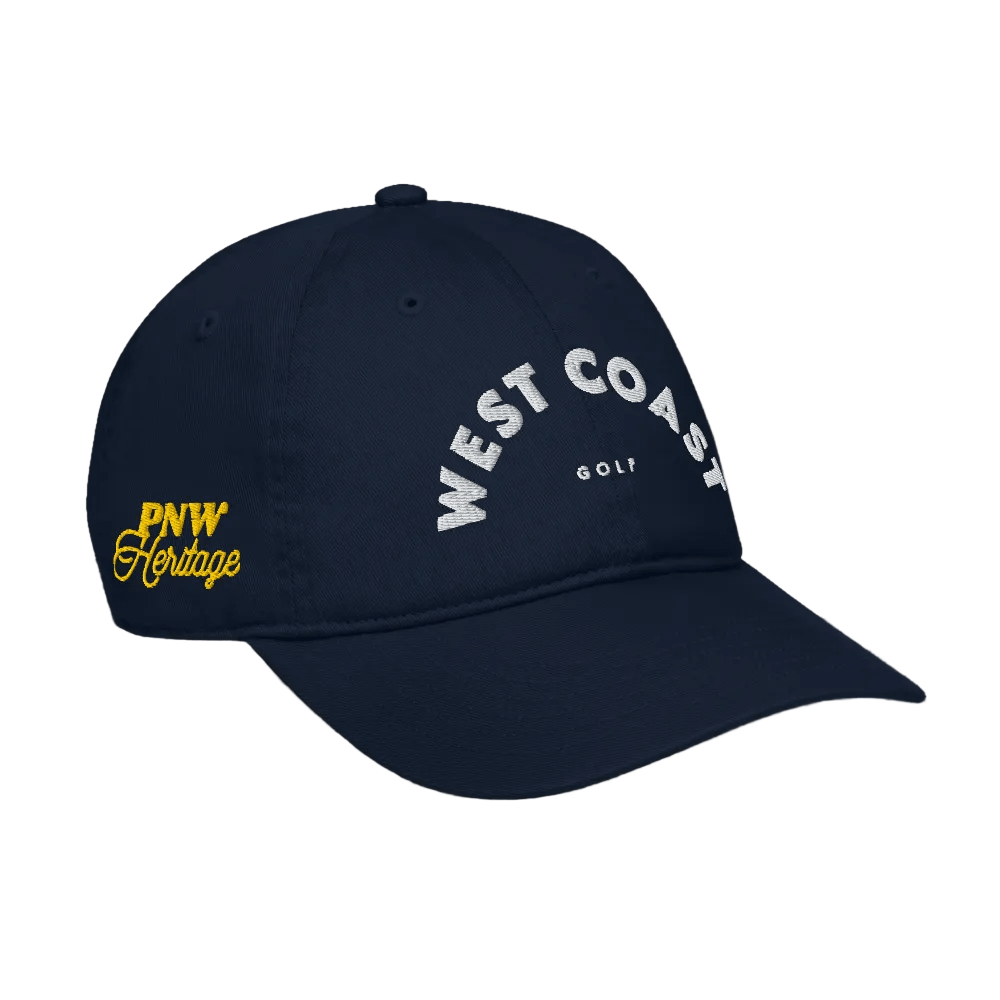Navy blue cap with 'West Coast Golf' and 'PNW Heritage' text on a black background