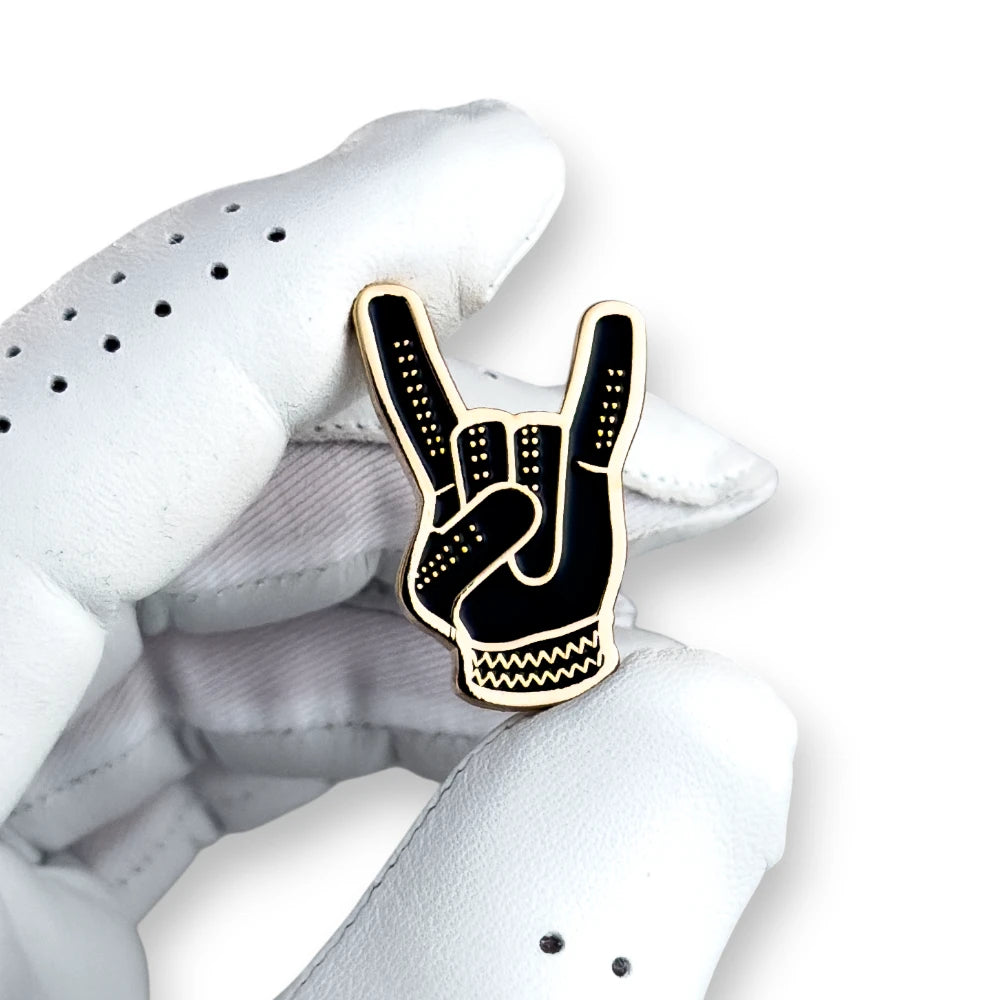 black and gold devil horns golf ball marker held in white golf glove