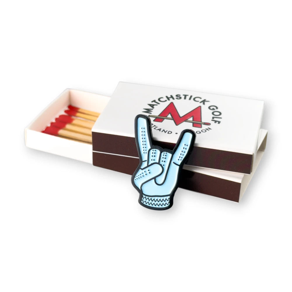 blue devil horns golf ball marker leaning on matchboxes