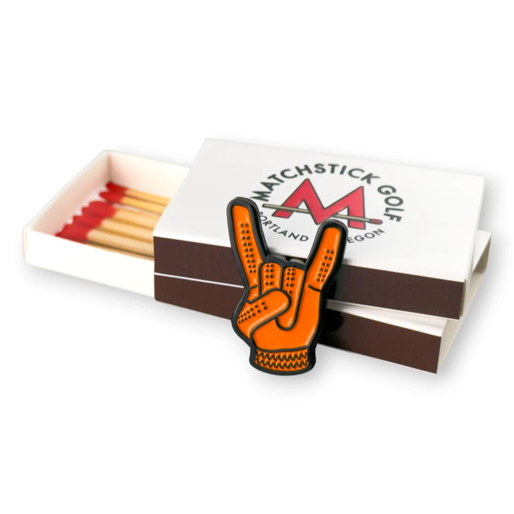 orange devil horns golf ball marker leaning on matchboxes