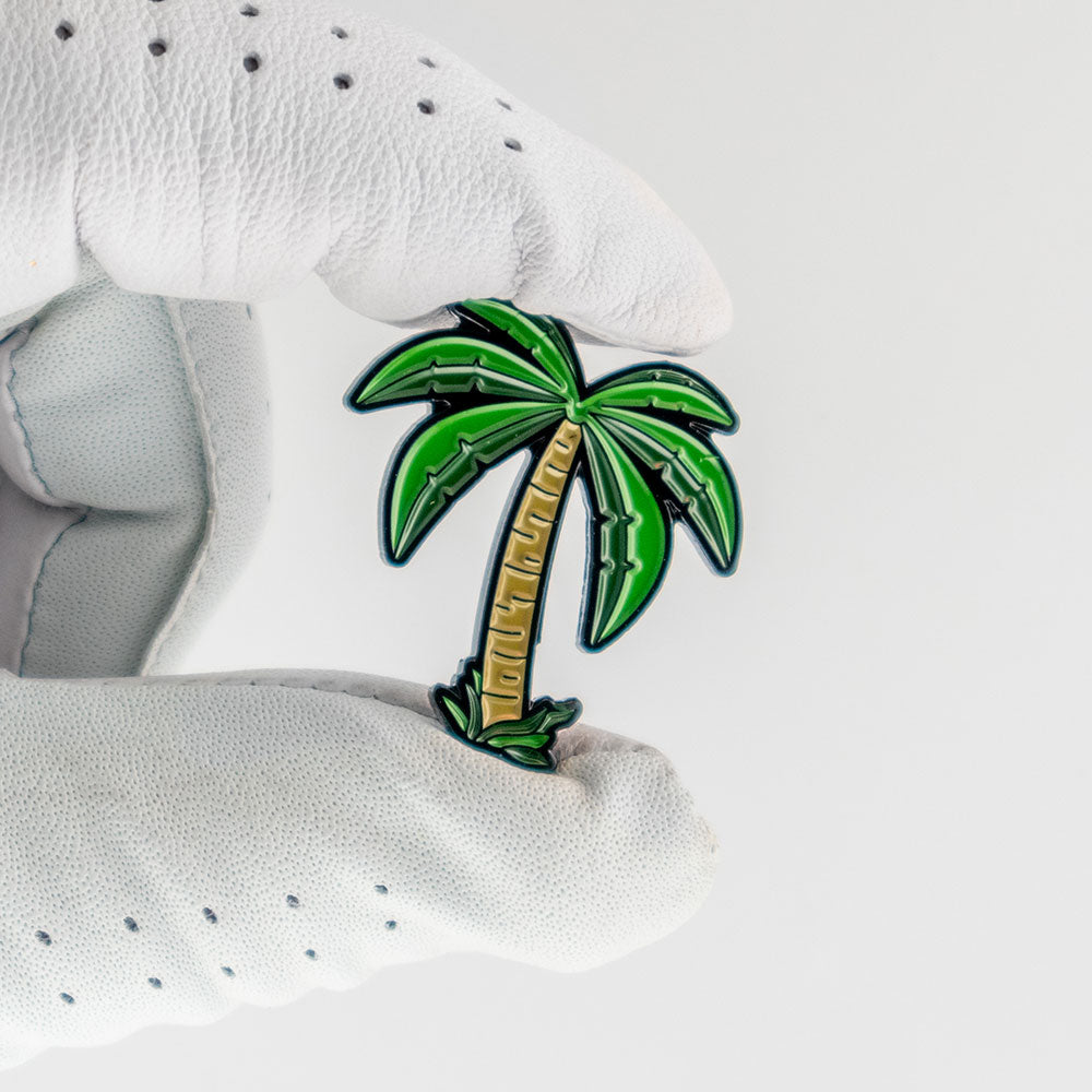 palm tree golf ball marker in glove hand