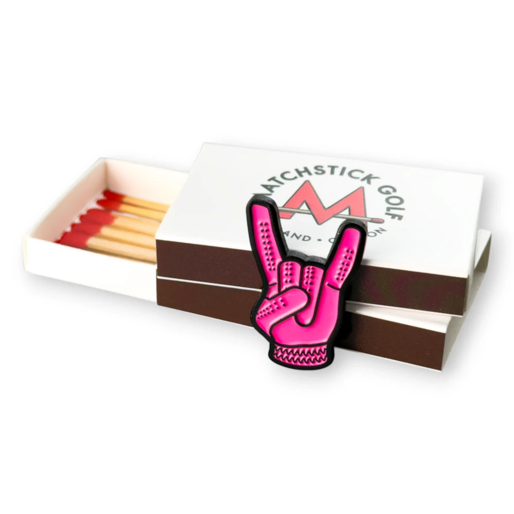 pink devil horns golf ball marker leaning on matchboxes