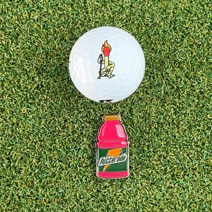 pink putterade golf ball marker on grass next to golf ball