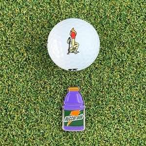 purple gatorade putterade golf ball marker on grass next to golf ball
