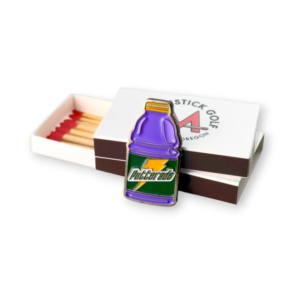 purple gatorade putterade golf ball marker leaned up against matchbox packaging