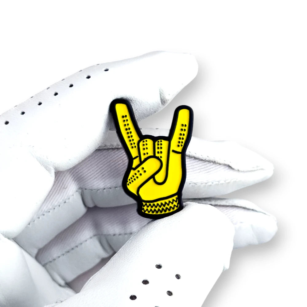 yellow devil horns golf ball marker held in white golf glove