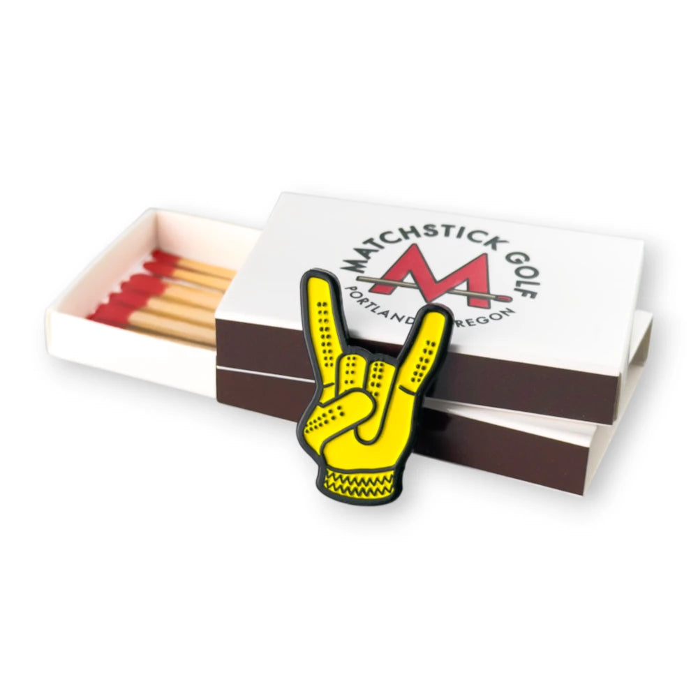 yellow devil horns golf ball marker leaning on matchboxes