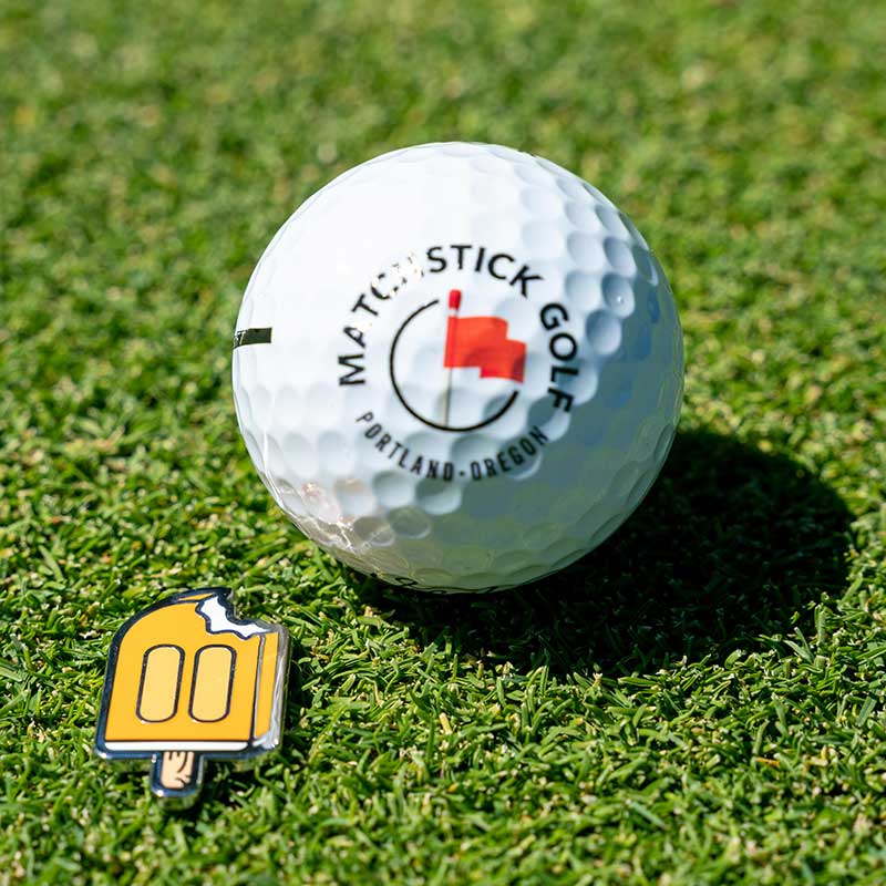 orange creamsicle golf ball marker with golf ball on green