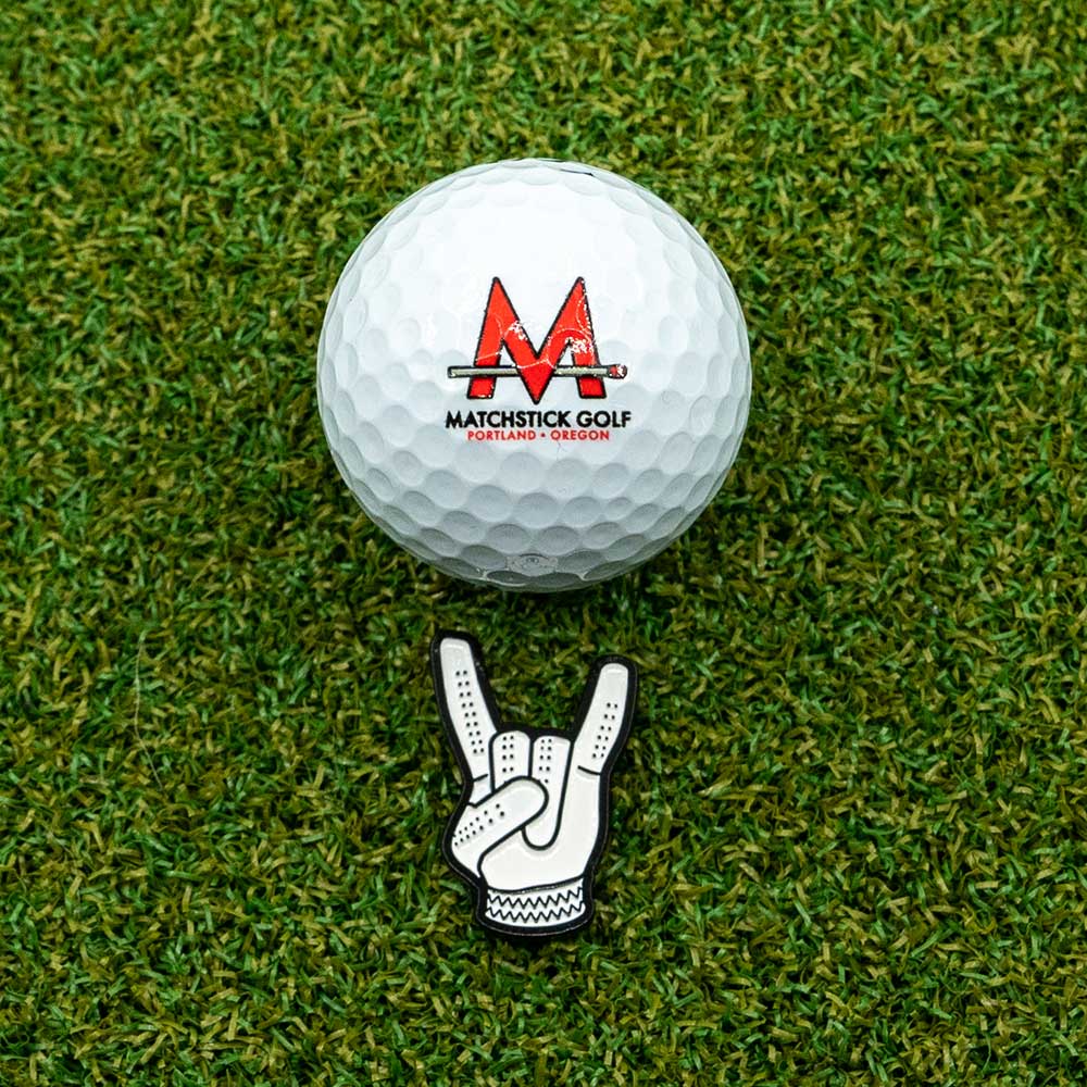 devil horns golf glove ball marker on grass with golf ball