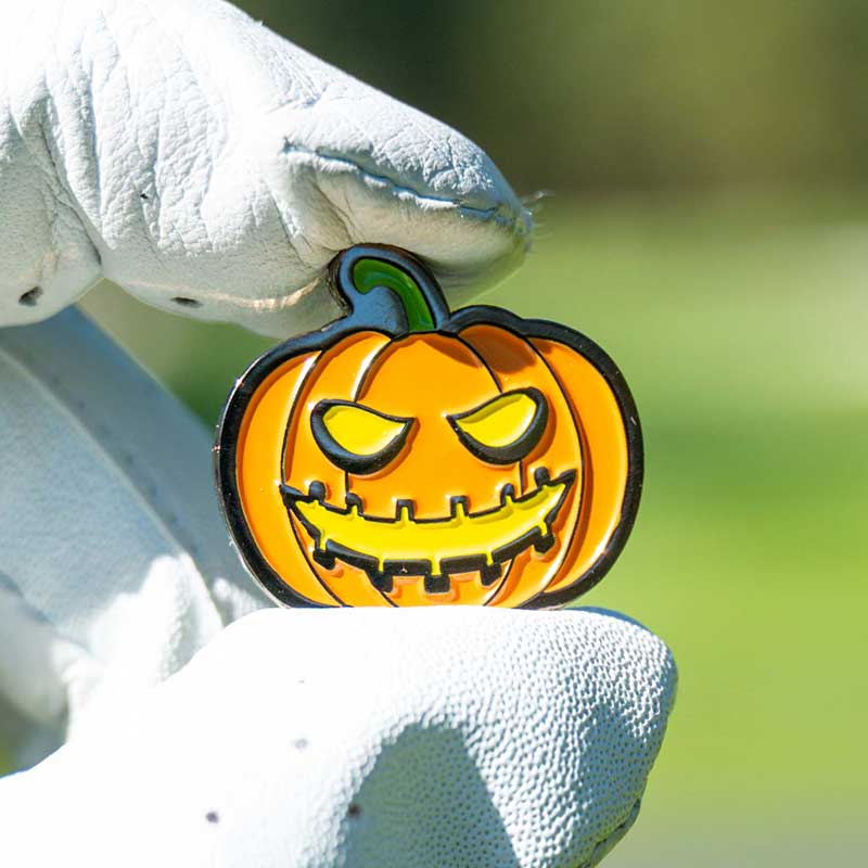 halloween jack-o-lantern golf ball marker held in golf glove