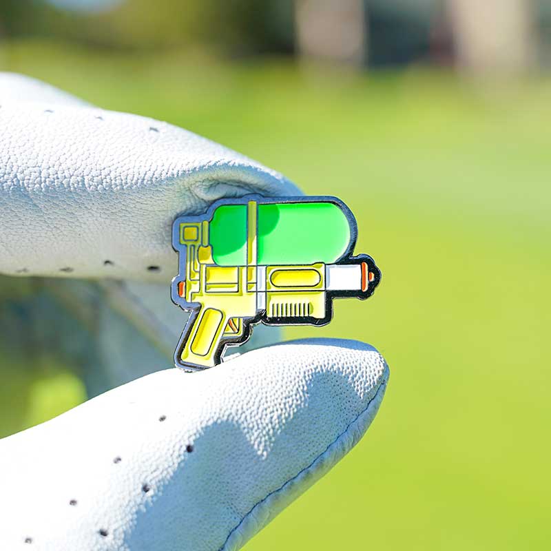 squirt gun golf ball marker held in golf glove fingers in sun