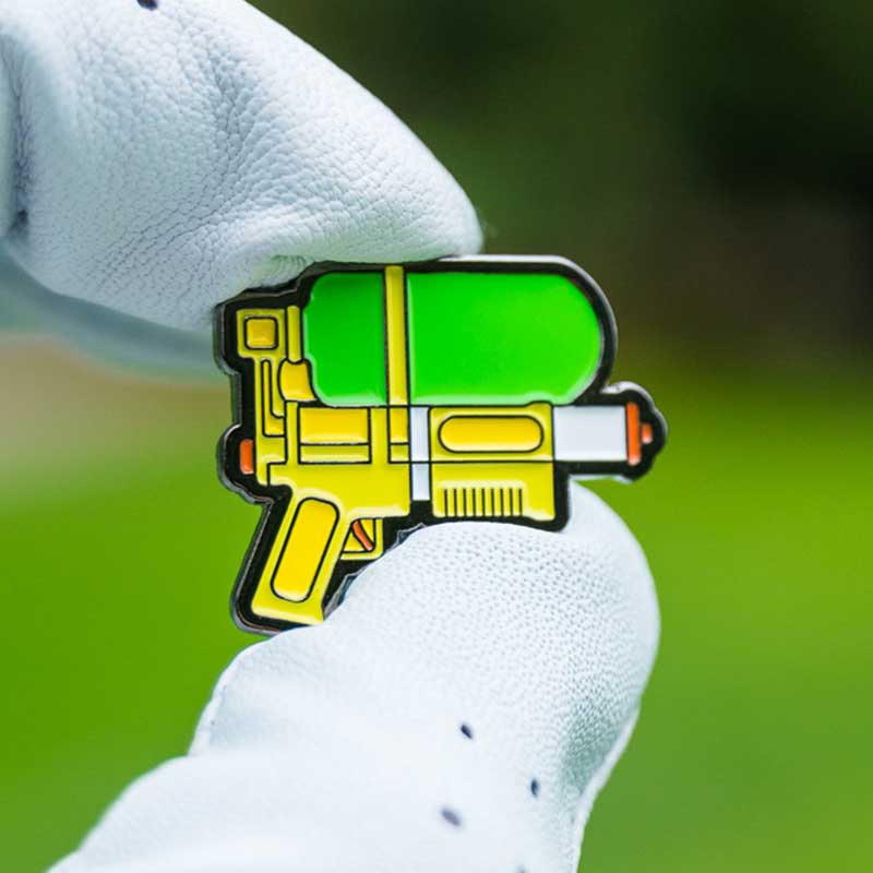 squirt gun golf ball marker held between golf glove fingers
